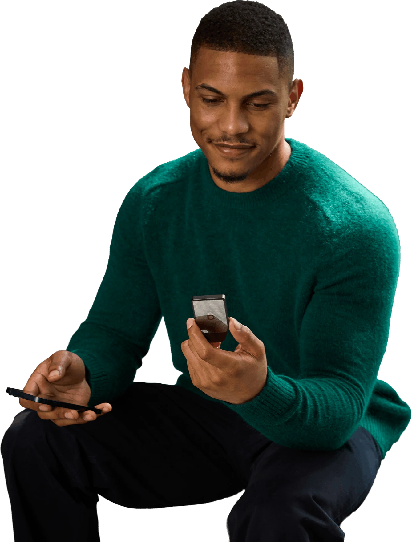 一位身穿绿色毛衣的男子坐着微笑,手中持有 Trezor Safe 7 硬件钱包和一部智能手机。